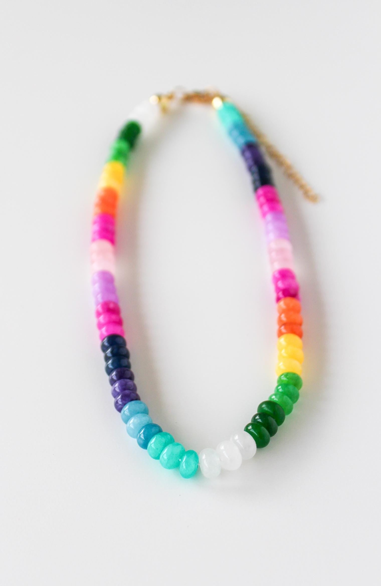 a multicolored beaded necklace on a white surface
