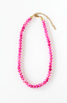 a pink beaded necklace on a gold chain