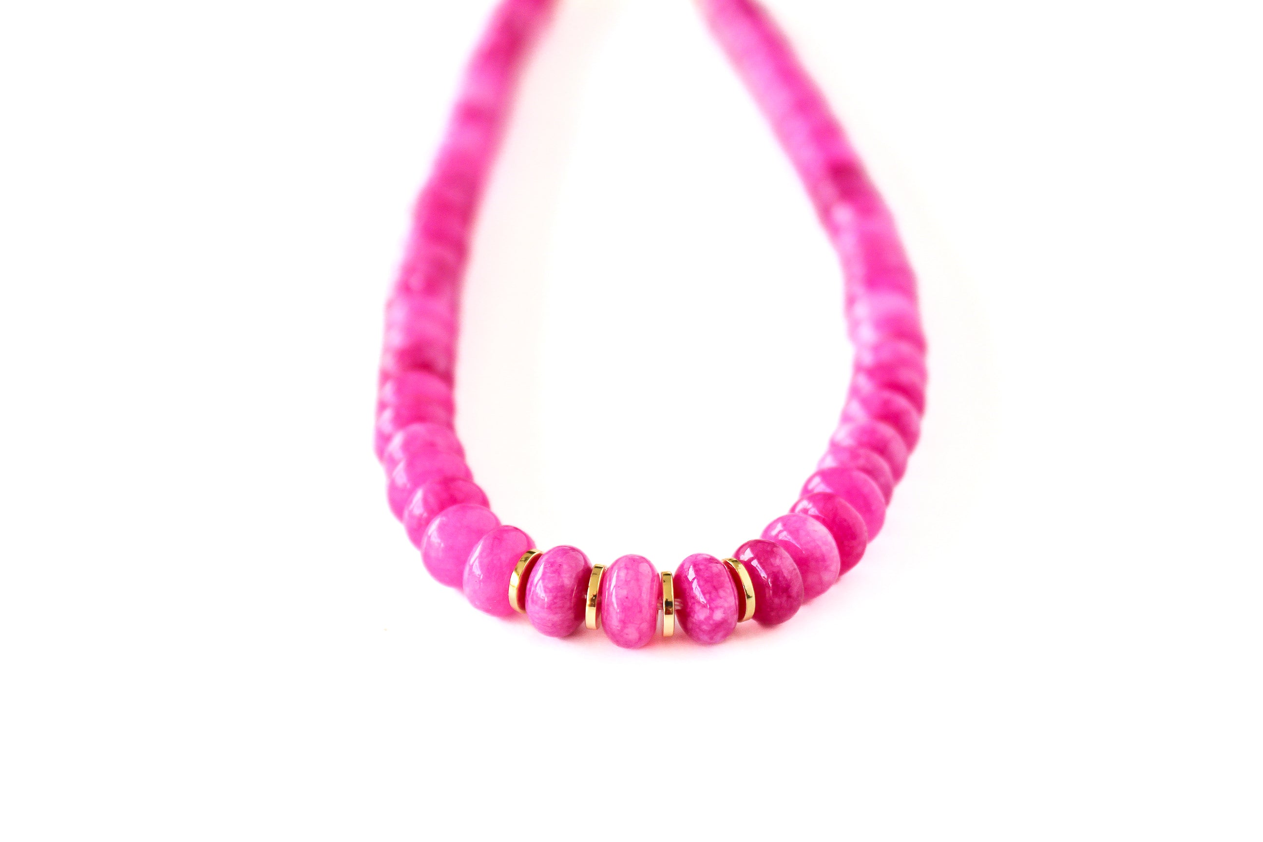 a pink necklace with gold beads on a white background